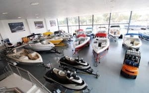 A spacious marine dealership showroom with boats, jet skis, and other watercraft on display. Large windows provide natural lighting, while an organized inventory management system ensures efficient tracking of assets. Advanced live video monitoring and AI security monitoring help protect valuable inventory, enhancing commercial property security and theft prevention. Surveillance for dealerships includes loitering deterrents and business security solutions to safeguard against unauthorized access and keyless theft risks.