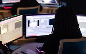 A security professional monitors multiple screens in a high-tech surveillance control room, analyzing live video feeds and AI-powered forensic footage. The dimly lit environment highlights the role of real-time video monitoring in detecting threats, preventing security incidents, and reducing liability risks for businesses and property owners.