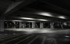 A large commercial truck is parked in an unauthorized area at a commercial property at night, illuminated by bright security lights. The image highlights the risks of unauthorized truck parking and potential cargo theft. AI-powered security solutions, such as live video monitoring and license plate recognition (LPR), can help detect and deter these security threats in real time.