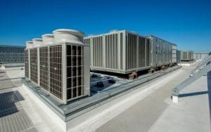 A rooftop HVAC system with large industrial air conditioning units under a clear blue sky. The image highlights the vulnerability of commercial HVAC units to copper theft and the importance of securing these high-value assets with live video monitoring and physical security measures.