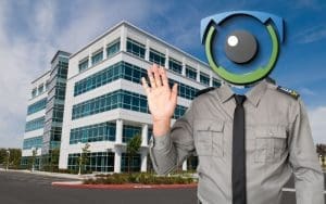 A futuristic AI-powered security guard with a surveillance camera for a head, standing in front of a modern commercial office building. Virtual Guard technology enhances property security with real-time AI monitoring and proactive crime prevention.
