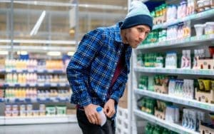 A retail store security camera captures a suspected shoplifter hiding an item in their jacket. Live video monitoring with AI-powered analytics helps detect and deter theft in real-time, improving loss prevention strategies for retailers.