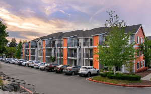 Exterior of a modern multifamily apartment complex with a full parking lot, illustrating the importance of live video monitoring for tenant safety and lease compliance.