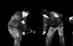 Thermal image of two intruders in hooded jackets attempting to breach a fenced area at night, captured by a remote video monitoring security system.