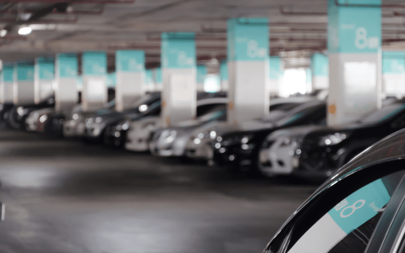 A row of parked cars in a multi-level parking garage with teal signs marking section 8 on each column, creating a uniform and structured layout.