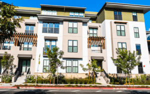Modern multifamily residential building with large windows, clean architectural lines, and landscaped surroundings, representing contemporary urban housing.