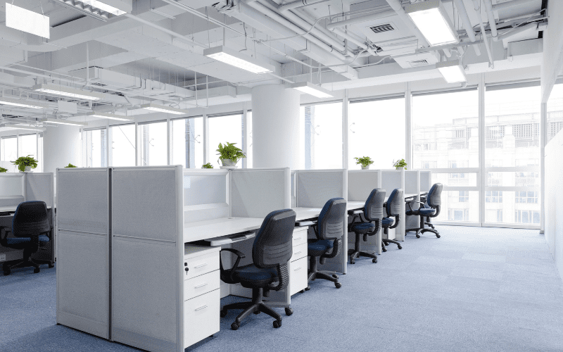 An empty, well-lit office space with cubicles, illustrating the importance of vacant property security to prevent unauthorized access or damage.