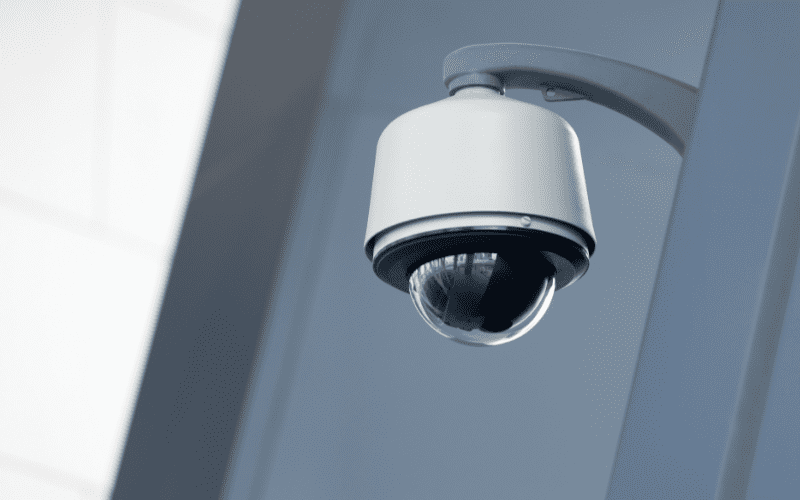 Close-up of a modern dome security camera mounted on a wall inside a commercial building, emphasizing its sleek design and positioning for indoor video monitoring.