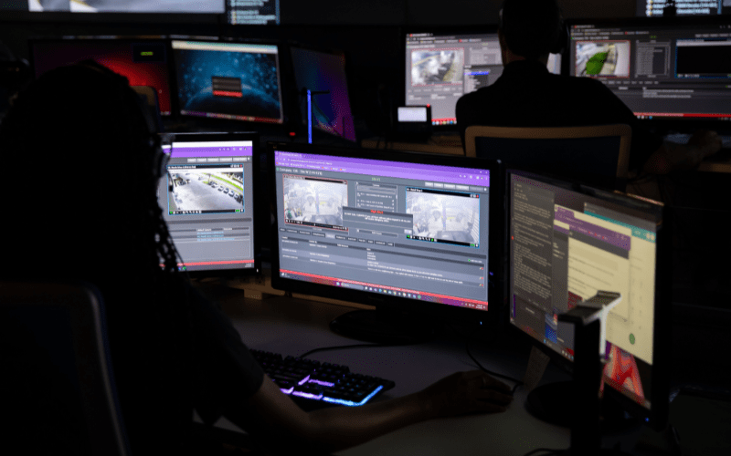 Security Operations Center (SOC) with operators monitoring multiple surveillance feeds on large computer screens, illustrating real-time remote monitoring by virtual security guards.