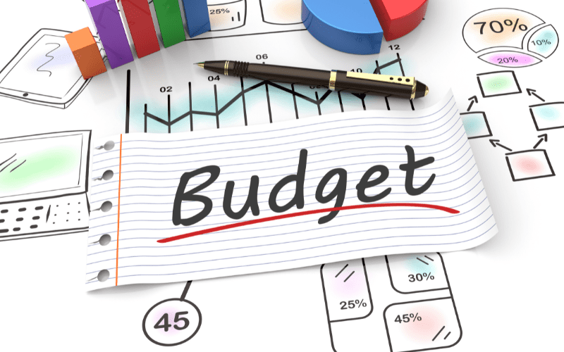 A budget planning concept featuring a notepad labeled "Budget," surrounded by financial charts, pie graphs, and a pen.