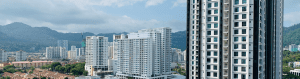 High-rise commercial and residential buildings in a cityscape with mountains in the background, viewed from an elevated perspective under partly cloudy skies.