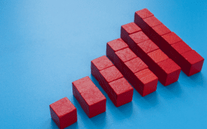 Red building blocks arranged in ascending order on a blue background, representing scalable growth or an upward business trend in security infrastructure.
