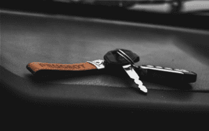 Close-up of a car key fob with a leather tag resting on a dashboard, representing a vehicle equipped with a passive engine immobilizer system.
