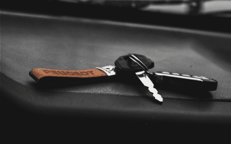 Close-up of a car key fob with a leather tag resting on a dashboard, representing a vehicle equipped with a passive engine immobilizer system.