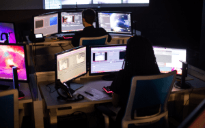 Security operators monitoring multiple live camera feeds at a centralized control center, demonstrating how remote guarding services provide real-time surveillance and intervention across commercial properties.