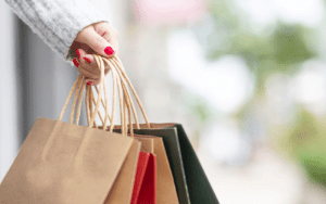 Close-up of a person holding multiple shopping bags outside a retail store, illustrating the need for security cameras for shops to monitor high-traffic areas, prevent theft, and improve safety in commercial environments.
