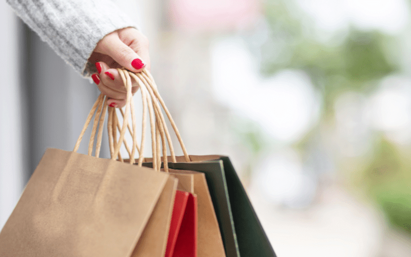 Close-up of a person holding multiple shopping bags outside a retail store, illustrating the need for security cameras for shops to monitor high-traffic areas, prevent theft, and improve safety in commercial environments.