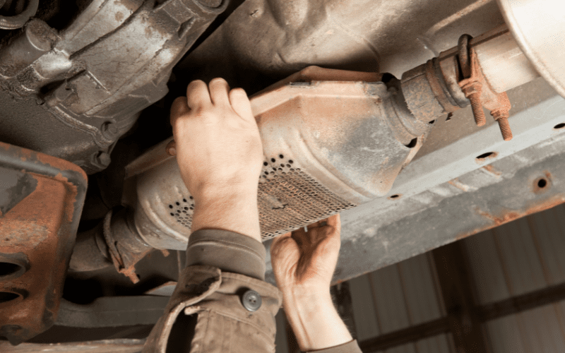 Mechanic working under a vehicle showing how to stop catalytic converter theft with protective measures
